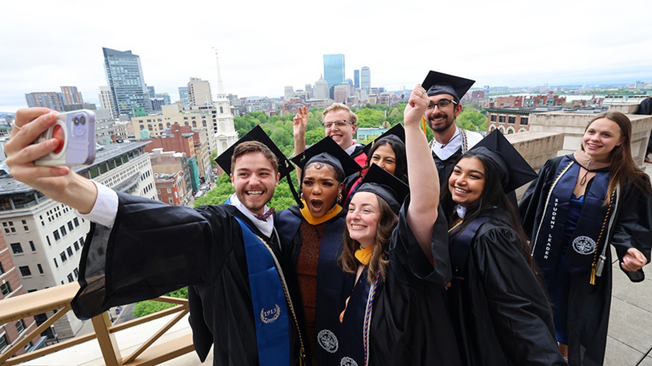 group of graduates taking a group photo with Boston in the background